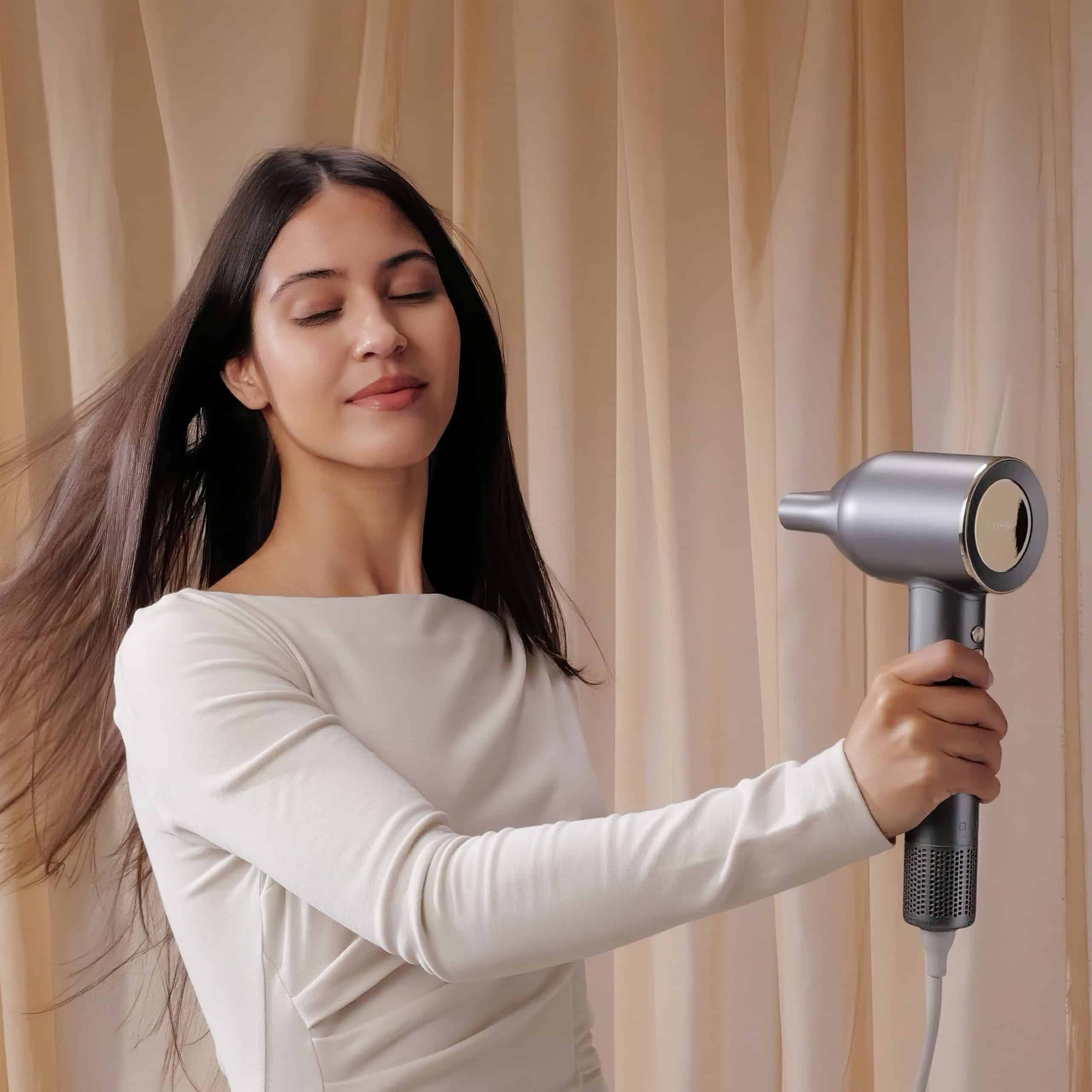 Modern silver hair dryer in use by woman with long hair.